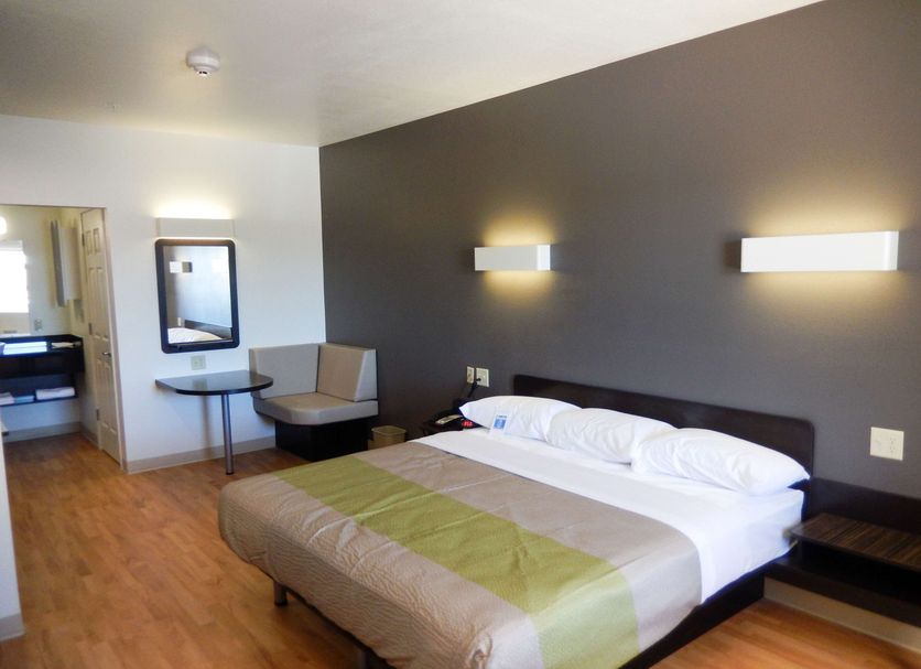 Studio 6 Yukon, OK guest room with king bed, seating area, desk and wood-look floors