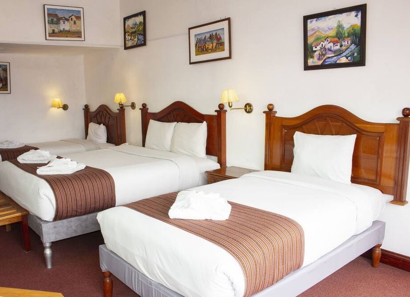 Hotel Amerinka in Cusco: twin beds in a guest room with wall art and bedside lamps