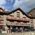 Hostal la Font in Os de Civís, stone alpine hotel with wooden balconies and mountain backdrop