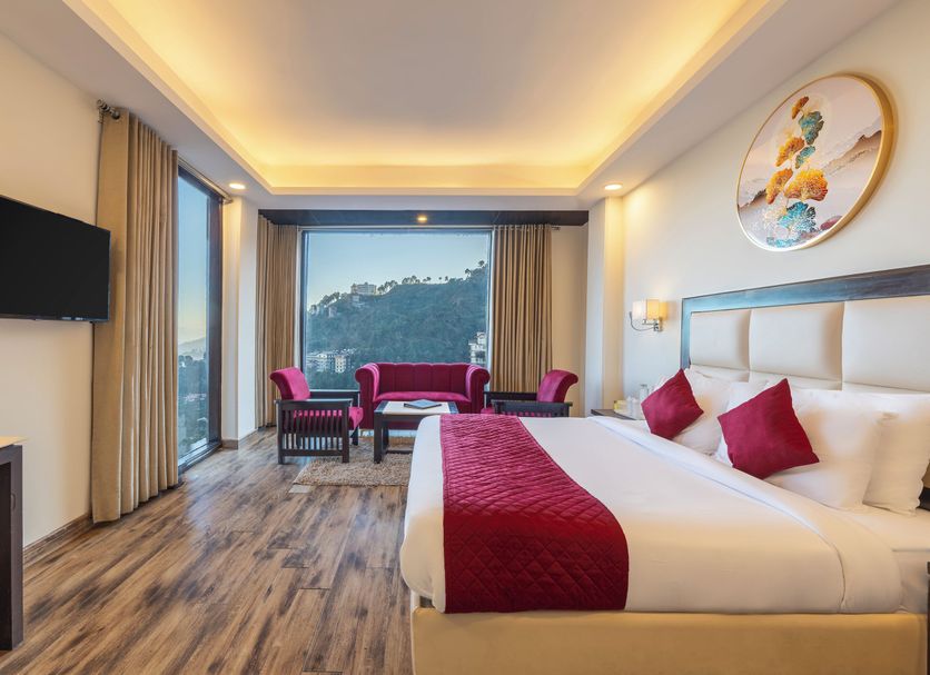 Snow Valley Resorts Shimla room with king bed, seating area, and hill view in Shimla