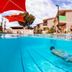 Onslow Beach Resort in Onslow: outdoor pool with swimmer, red umbrellas and resort buildings