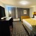 Baymont by Wyndham Chicago/Calumet City guest room with king bed, yellow sofa, and patterned carpet
