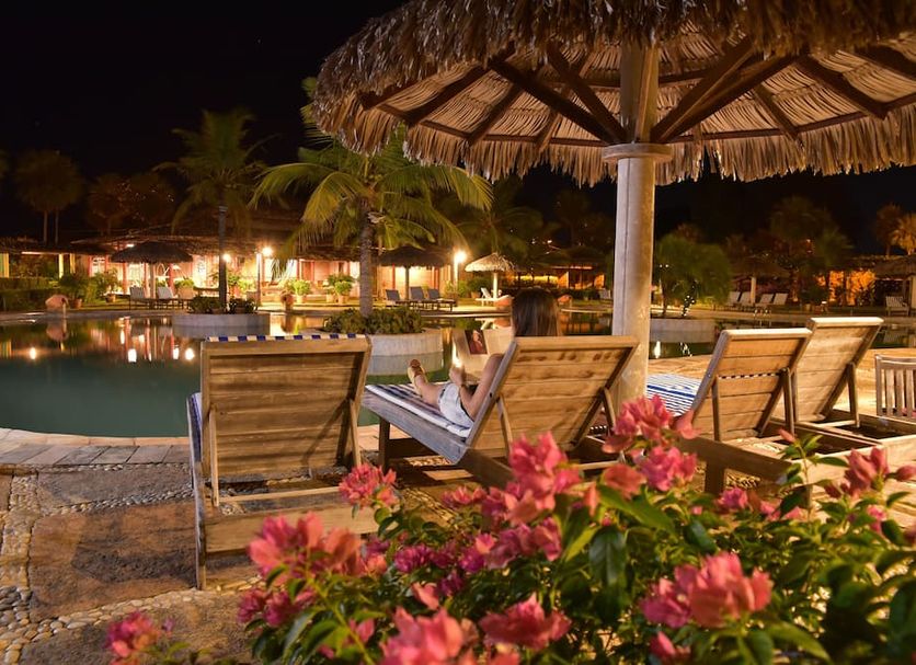 Porto Preguiças Resort in Barreirinhas: nighttime poolside lounge chairs and thatched umbrellas by the pool