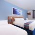 Travelodge Hull Central in Hull room with two beds, blue walls, window, desk, and wall-mounted TV