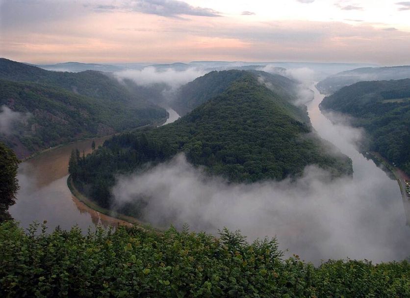 Hotel Restaurant Zum Schwan in Mettlach with misty river bend and forested hills at sunrise