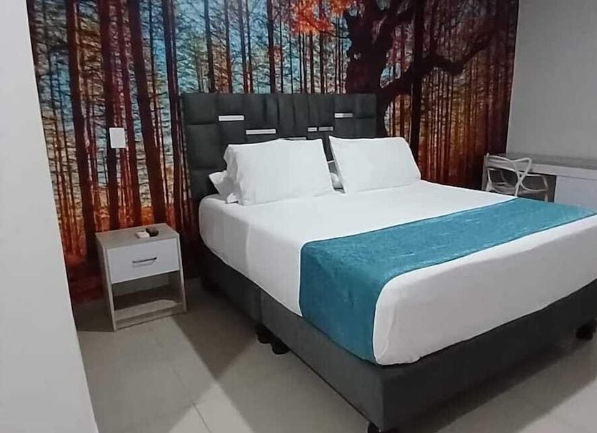 Hotel Granada Loft in Cali: double bed with teal runner and forest mural headboard