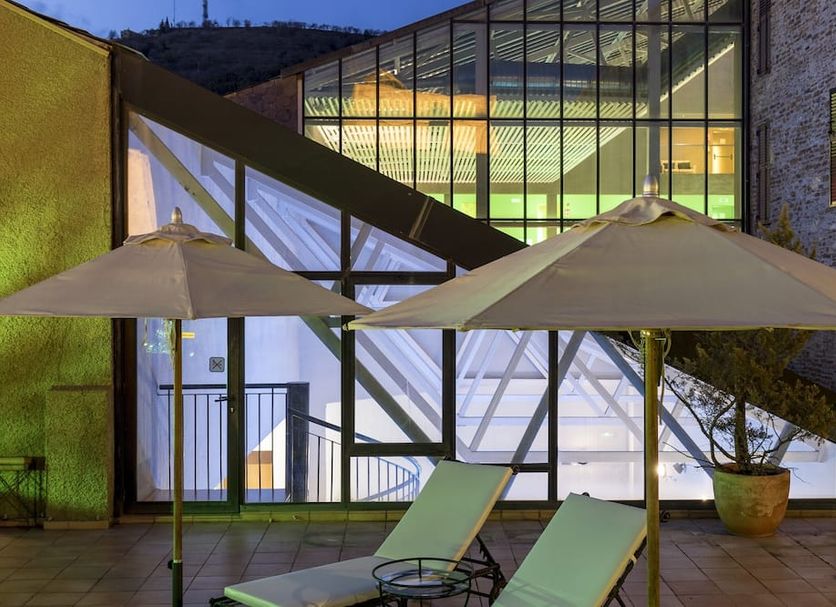 Parador De La Seu D'urgell terrace with lounge chairs, umbrellas and glass-lit atrium in La Seu d'Urgell