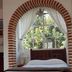 Suites Santo Domingo in San Miguel de Allende bedroom with brick-arched window and sheer curtains
