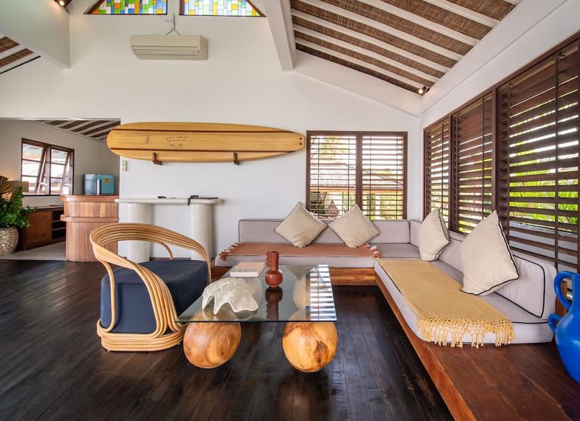 Bombora Medewi in Pekutatan: airy lounge with surfboards, wood-beam ceiling, and cushioned seating
