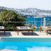 Rhenia Hotel in Tourlos with poolside loungers and a view over the blue bay and hillside.