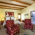 Evergreen Manor and Spa Stellenbosch guest room with king bed, red armchairs and ensuite bathroom doorway