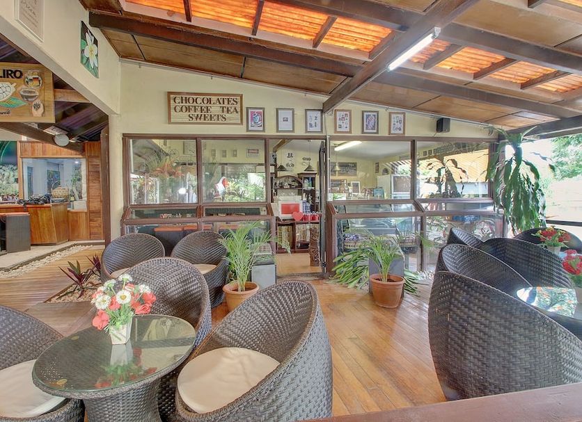 Honiara Hotel in Honiara with a covered café lounge, wicker seating, glass tables and indoor plants