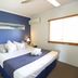 Cairns Beach Resort room in Holloways Beach with king bed, bedside lamps, air conditioner and window blinds