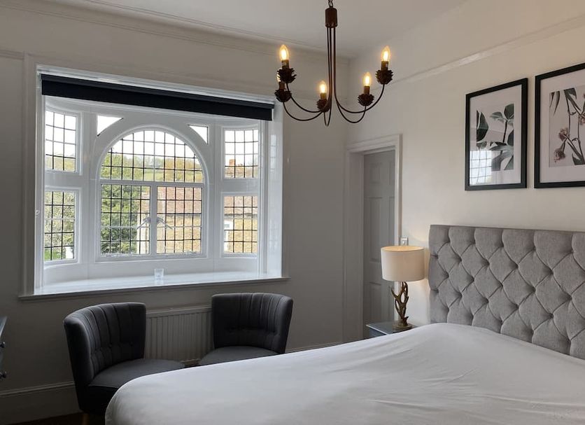 Castle Hotel Dartford guest room with tufted bed, bay window seating and chandelier