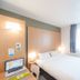 B&B HOTEL Montluçon guest room with double bed, desk, laptop, and window with curtains