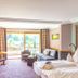 Hotel Heselbacher Hof in Baiersbronn guest room with sofa, bed, and balcony doors to scenic view