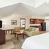Hampton Inn by Hilton Colchester guest room with king bed, seating area, kitchenette and TV