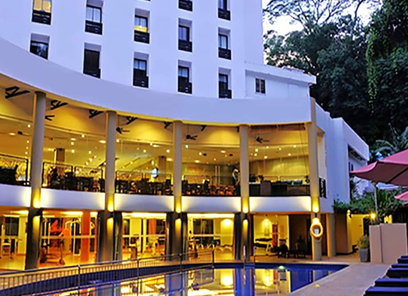 The Palace Hotel Kota Kinabalu with illuminated poolside terrace and outdoor seating at dusk