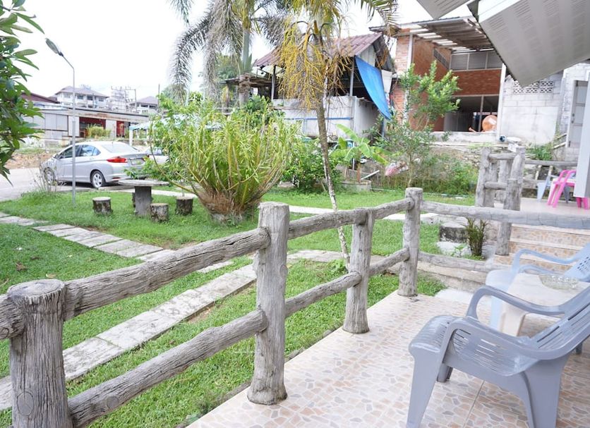 Dahla House Ranong in Mueang Ranong with a garden patio, wooden fence, and plastic chairs