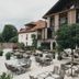 Outdoor terrace with tables and chairs at Hotel Eibl-Brunner in Frauenau, beside a modern building and trees.
