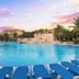 Hotel Marina El Cid Spa in Puerto Morelos with a large resort pool, lounge chairs and sunset sky