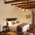 Hotel Boutique Castillo Rojo in Santiago guest room with exposed beams, king bed, and seating area