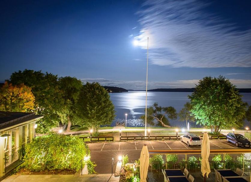 Sigtuna Stadshotell in Sigtuna with lake view, lit waterfront promenade, and outdoor seating at dusk