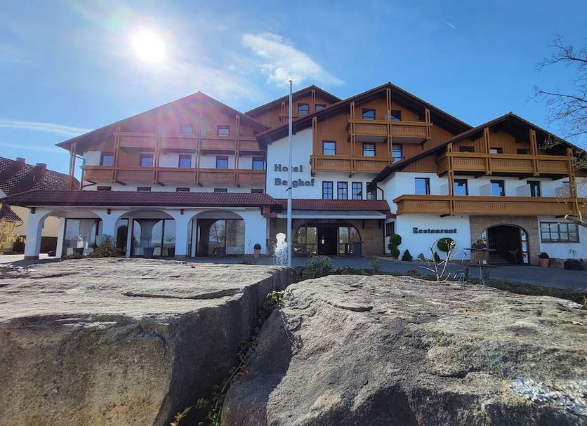 Hotel Berghof in Petersberg, alpine-style hotel exterior with sunlit facade and rocky foreground
