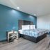 Studio 6 Suites Perris, CA guest room with king bed, desk, TV and blue accent wall