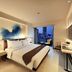 Midtown Hotel Surabaya room with king bed, wall-mounted TV and city view balcony