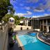 Twin Towers Inn in Artarmon with an outdoor pool and courtyard seating under a partly cloudy sky.
