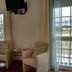 Karibu Aruba in Noord: guest room with two armchairs, wall-mounted TV, and balcony doors overlooking pool area.
