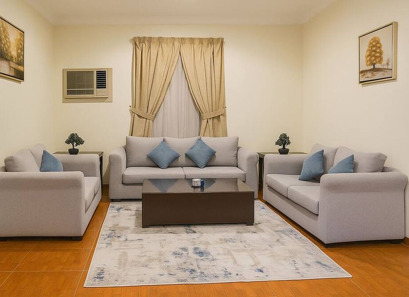 Almawasem Alarbaa Hotel Suites in Tabuk living room with sofas, coffee table, rug and curtained window