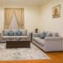 Almawasem Alarbaa Hotel Suites in Tabuk living room with sofas, coffee table, rug and curtained window