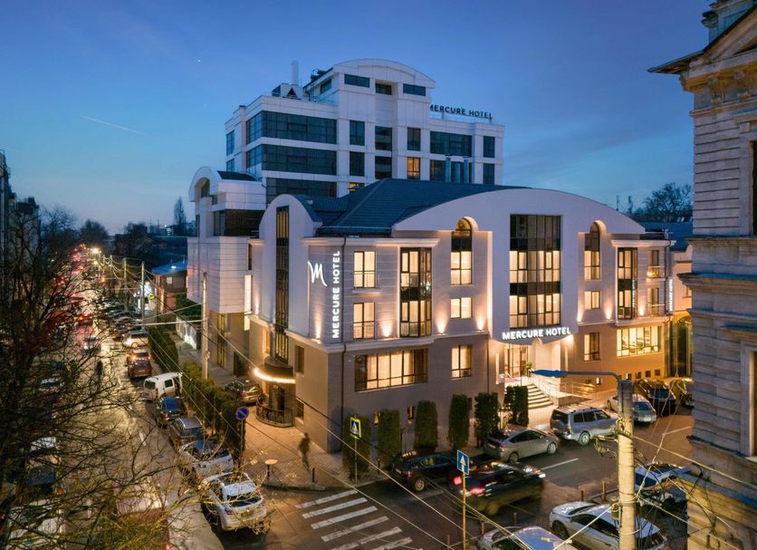 Mercure Chisinau Center Jazz Hotel in Chisinau at dusk, with illuminated modern facade and city street below