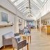 Hotel Pinenhus in Glyngøre: bright skylit lounge with gray armchairs, tables, and a wooden bar