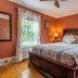 The Stella Rose B&B room in Wolfville with a wooden bed, orange walls, and bright windows