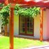 Sans Souci Inn in Pohara with covered patio, vine-covered pergola, and lawn outside guest rooms