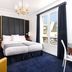 Melia Paris Champs Elysees room with king bed, blue carpet, chandelier and Paris window view