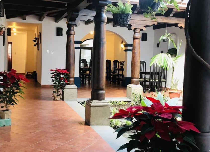 Hotel la Galería in Antigua: courtyard with arches, dark wood columns, potted red poinsettias and dining chairs