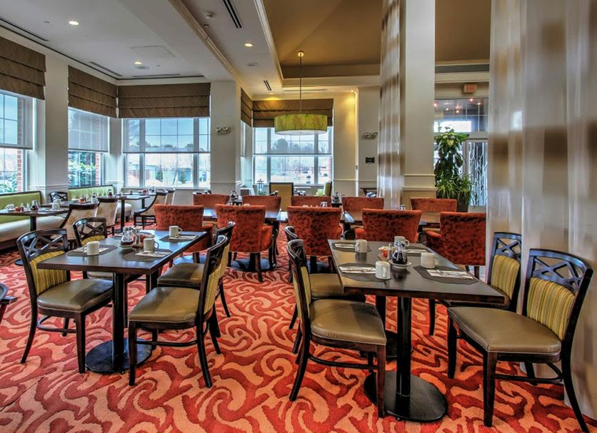 Hilton Garden Inn Williamsburg dining area with tables, chairs, large windows, and red patterned carpet