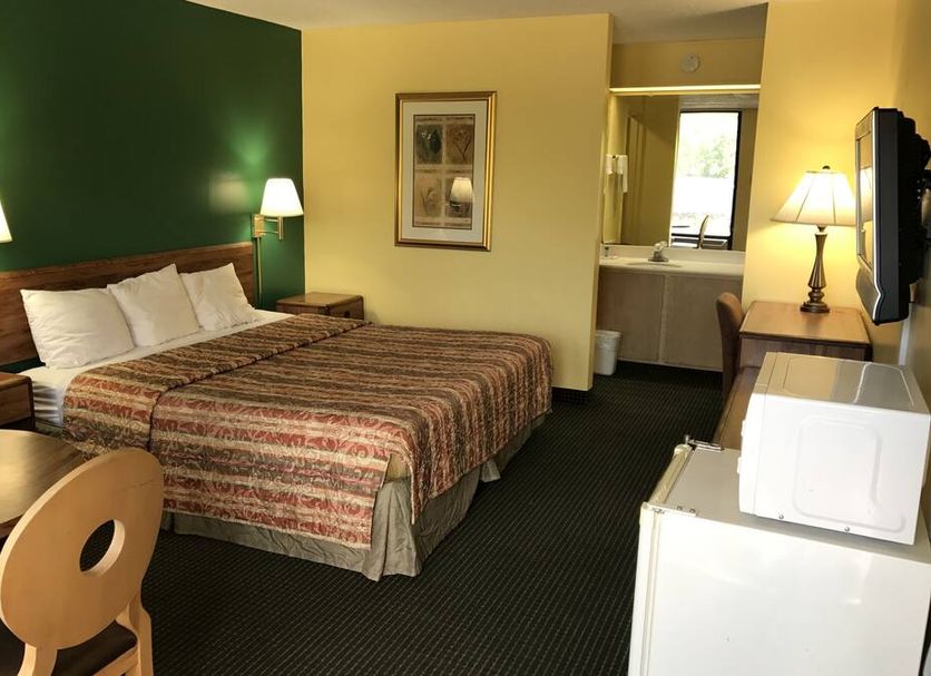 Relax Inn & Suites Dublin guest room with two beds, lamps, desk, and bathroom doorway