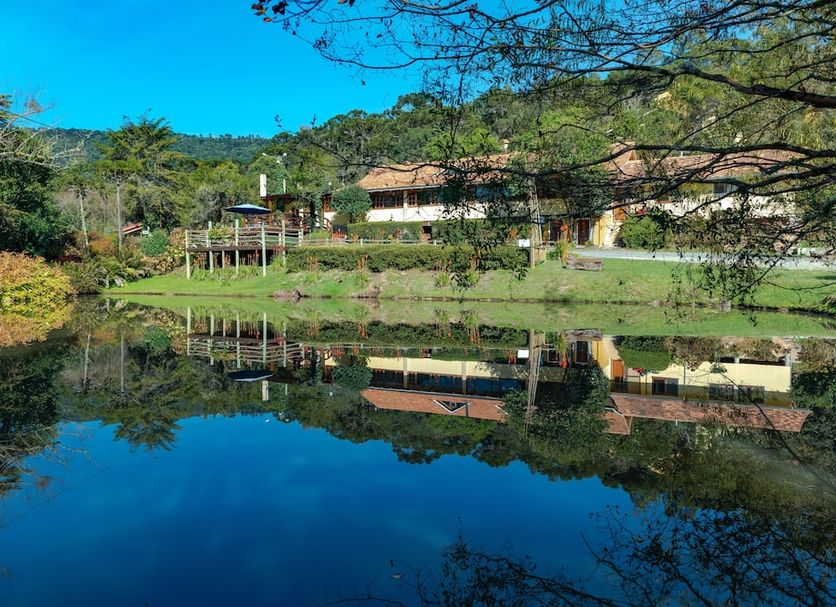 Serra Bela Eco Pousada in Urubici with lakeside cabins reflected in a calm pond and forested hills