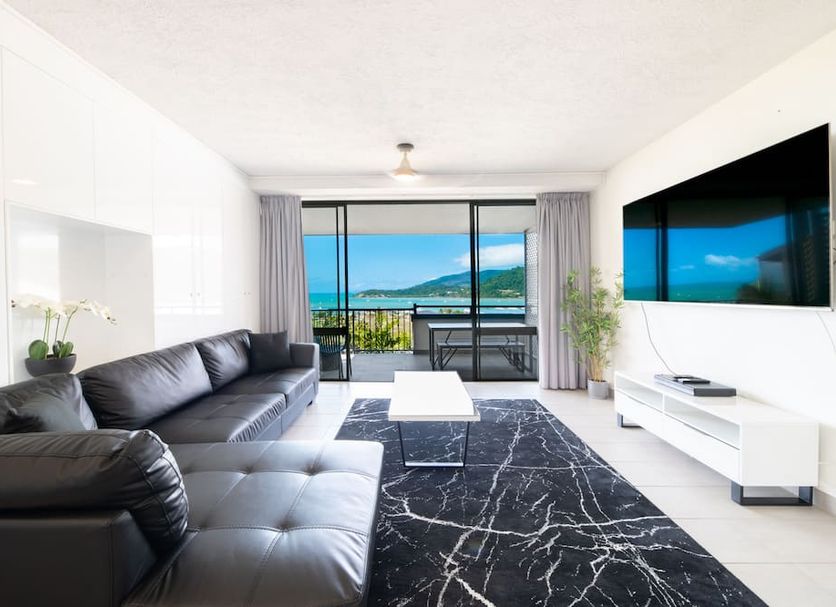 Whitsunday Terraces Resort in Airlie Beach living room with balcony ocean view and wall-mounted TV