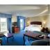 Hampton Inn & Suites Lake Wales guest room with king bed, sitting area, and blue curtains