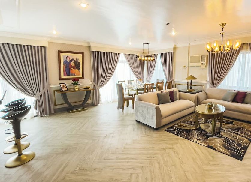 Miramar Hotel Manila lounge with beige sectional sofa, dining table and large windows with drapes