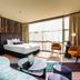 Naumi Hotel Wellington guest room with king bed, seating area, and floor-to-ceiling windows in Wellington