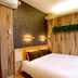 Guesthouse Nara Komachi room in Nara with a double bed, wall-mounted lights, and wood-paneled walls