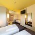 B&B Hotel Oberhausen am Centro guest room with twin beds, yellow ceiling, and wall-mounted TV