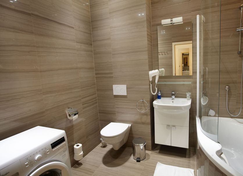 Residence U Cerne Veze bathroom with bathtub, sink, toilet and washing machine in České Budějovice